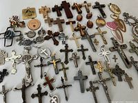 Overview of the full lot showing a variety of crosses and crucifixes arranged on a white surface, displaying different materials and sizes.
