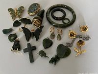 Full lot of 20 green jade style vintage pieces spread on white background featuring jewelry items including bangles, pins, earrings, and charms.