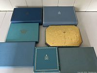 Seven vintage BIRKS jewelry presentation boxes of various colors and conditions arranged on a flat surface