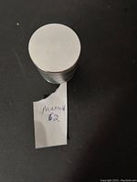 Top view of closed metal herb grinder, cylindrical and silver in color.