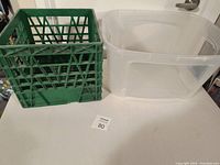 Photo showing green plastic crate and clear plastic storage bin on a white table.