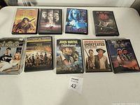 Photo showing 9 DVD cases arranged in two rows on a white surface, featuring well-known movie titles.