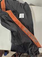 Black wind pants with an orange side stripe featuring the Harley-Davidson logo in grey.