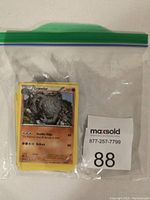 Plastic bag with Pokemon trading cards including a Graveler card showing 100 HP and moves Double-Edge and Rollout