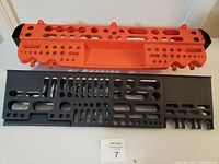 Top view of black and orange wall-mounted screwdriver holders showing multiple slots and compartments for holding screwdrivers and other tools.