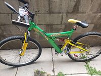 Side view of the green and yellow Star Speed Trax mountain bike showing the full frame, 26-inch knobby tires, rear suspension, and 21-speed gear setup.