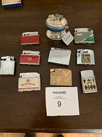 Full set of 10 assorted vintage lighters arranged on a table including different shapes, colors and finishes.