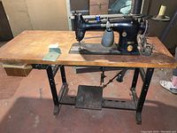 Full view of the Singer industrial sewing machine Model 96K41 mounted on original wooden table with black metal frame base and foot pedal.