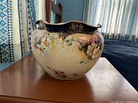 Front and side view of the large ceramic pot showing floral decoration and blue scalloped rim.