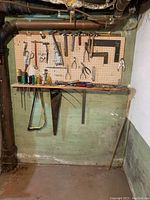 Full view of pegboard wall with assorted tools mounted including saws, levels, squares, pliers, and screwdrivers.