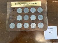 Front view of walnut plaque with 15 silver-tone metal tokens, 2 slots empty, header label visible.