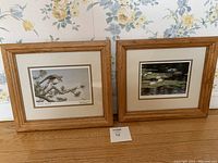 Two framed fine art prints by Don Li-Leger side by side, showing "Prairie Falcon" on left and "Waterlilies And Mallards" on right, both in oak frames.
