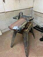 Side view of the cabinetmakers belt sander on metal stand with sanding belt visible, showing condition and size.