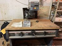 Front view of Sears Craftsman radial arm saw showing worktable, saw blade, instruction manual, and additional 8 inch molding and dado guard box.