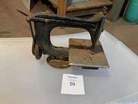 Overall view of vintage small Singer sewing machine from the side showing handwheel and sewing bed.