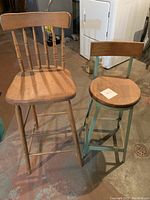 Both stools side by side on a concrete floor near laundry appliances, showing overall shape and condition.
