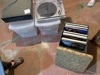 Photo showing the Technics SL82 turntable, SL-PD887 CD changer stacked on plastic storage bins, and a box of vintage vinyl records with its lid placed in front.