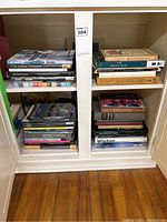 Photo of two stacks of assorted coffee table books in a white cabinet, showing multiple titles related to art and sculpture.