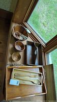Wooden serving bowls, trays, utensils arranged near window display.