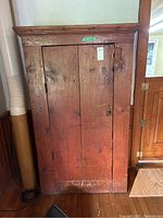 Front view of tall wooden cabinet showing single door and crown molding