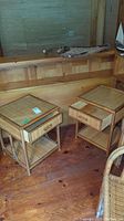 Two matching rattan nightstands with glass tops, drawers, and lower woven shelves shown side by side on a wood floor.