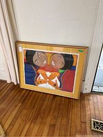 Framed painting shown leaning against wall on wood floor, visible artwork and signature