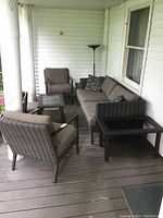 Overview of two armchairs, sofa, three tables and floor lamp on porch