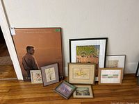 Collection of 8 framed artworks including a large poster and several small botanical drawings and prints arranged on floor leaning against wall
