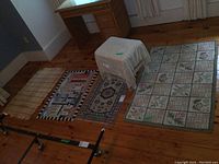 Photo of the 4 smaller rugs and a stool arranged on a wooden floor next to a desk