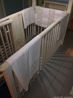 Five vintage white table cloths draped on white railings, some with visible marks and discoloration.