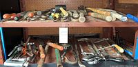 Wide view of assorted hammers, hand saws, and metal shears arranged on metal shelving