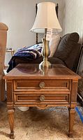 Side view of Francesca Drexel end table with table lamp on top showing wood finish and drawer pulls