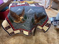 Photo of quilt with eagle artwork featuring mountains, pine trees, and eagles in flight, bordered with themed blocks.