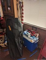 Black carrying case for folding chair next to American flags and Rubbermaid cooler.
