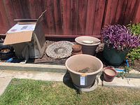 Overview showing assortment of pots, purple plant, bird bath top, and Bernini fountain in box
