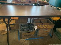 Folding table with wooden and metal crates underneath, brown finish, damage visible on one end.