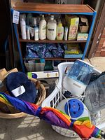 Wide view of shelf with various toiletries including lotions, bottles, and toiletry bags, plus multiple household items such as umbrellas, laundry baskets, a humidifier, and a travel neck pillow.