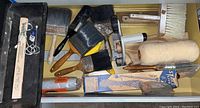 Top drawer with various paint brushes, paint tray liner, paint roller sleeve, and power paint roller attachment.