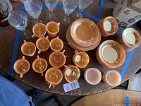 Full overhead photo showing peach luster cups, saucers, and clear wine glasses arranged on a table.