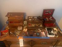 Overview of entire lot on wooden table showing boxes, watches and small jewelry pieces