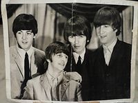 Full front view of the black and white photograph showing all four Beatles members with crease down center.