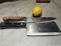 Photo showing the two knives side by side on a marble surface with a lemon for scale.