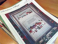 Christmas Village needlepoint pattern booklet showing completed sampler on cover with Santa and village scene.