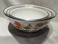 Three enamelware nesting mixing bowls stacked inside each other showing size differences and floral pattern.