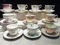 View of all ten bone china cups with matching saucers arranged in two rows, showing diverse floral designs and various English makers.