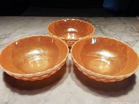 Photo showing three peach-colored bowls arranged on a surface, highlighting their size, color, and pattern.