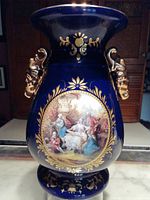 Front view of the cobalt blue Limoges vase showing the central painted classical scene and gold detailing with lion head handles