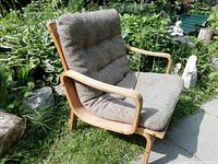 Side angled view of the lounge chair showing curved bentwood armrest and seat cushion.