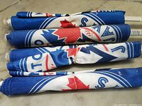 Photo showing four rolled-up Blue Jays flags with visible logo and maple leaf design.
