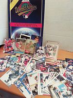 Photo showing a large 1992 World Series Toronto Blue Jays commemorative program standing at the back with over 40 assorted baseball and hockey cards laid out and stacked in front.